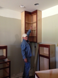 Bill reaching up to wall cabinet.